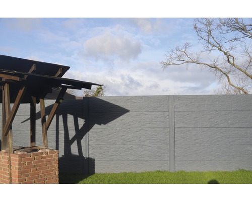 Vue du jardin avec clôture en béton et espace barbecue