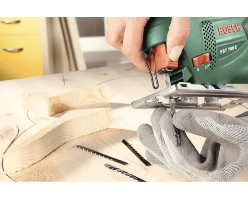 Scie sauteuse Bosch coupant du bois avec des gants et des lames de scie
