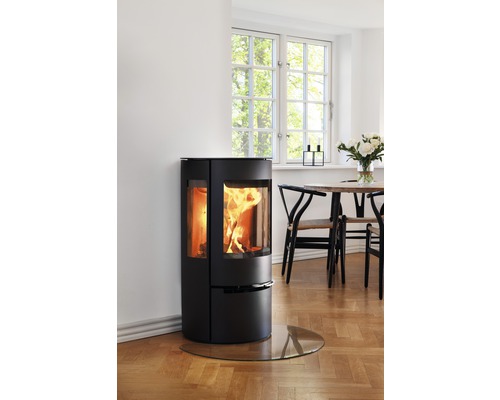 Kaminofen mit Glasbodenplatte in einem hellen Raum.