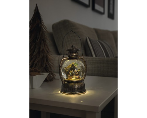 Lanterne décorative avec boule à neige et crèche sur une table