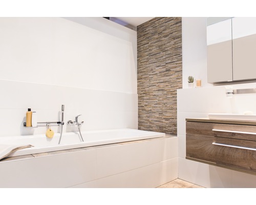 Salle de bain lumineuse avec baignoire, meuble-lavabo et carrelage mural