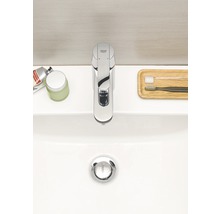 Aufnahme eines Waschbeckens mit einer Armatur der Marke Grohe, Zahnbürsten und Kosmetikprodukten