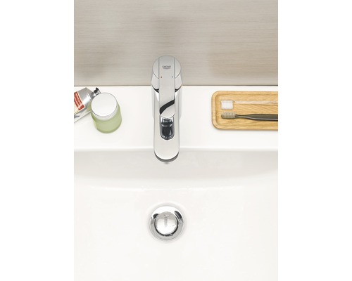 Aufnahme eines Waschbeckens mit einer Armatur der Marke Grohe, Zahnbürsten und Kosmetikprodukten