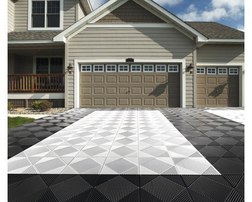 Einfahrt mit schwarzen und hellen Bodenfliesen vor einem Haus mit Doppelgarage