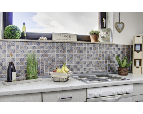 Scène de cuisine avec des carreaux de mosaïque, une plaque de cuisson, des décorations et des aliments sur un plan de travail.