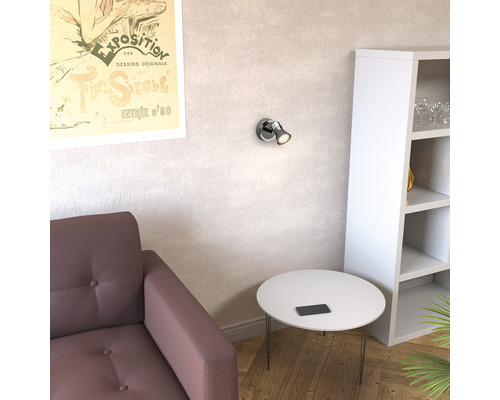 Wohnzimmer mit Sessel, Tisch, Regal und Wandleuchte