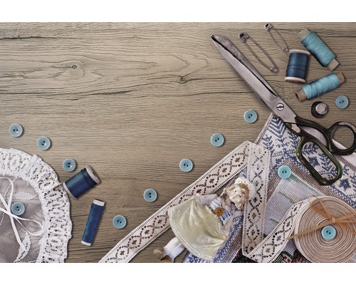 Scène de couture avec ciseaux, aiguilles, bobines de fil, boutons, dentelle et tissu sur une table en bois