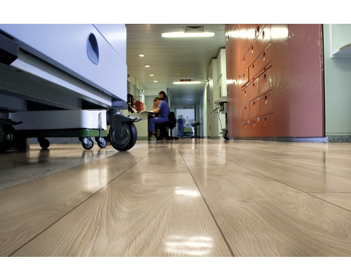 Plancher en bois clair dans un couloir d''hôpital avec des équipements médicaux et du personnel