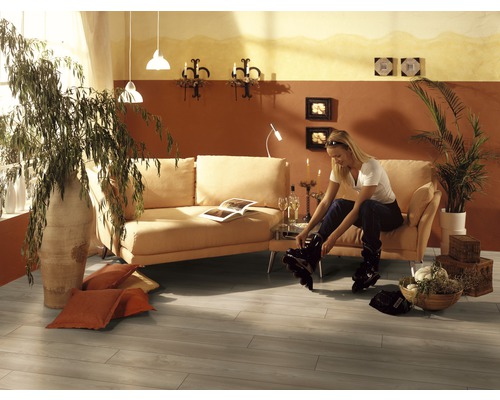 Salon avec canapé, plantes d''intérieur et femme mettant des rollers en ligne