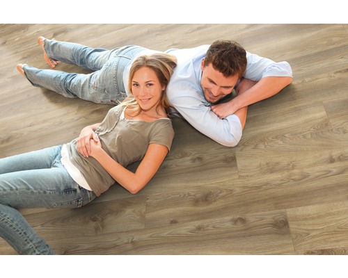 Un couple est allongé sur un sol stratifié en bois clair.