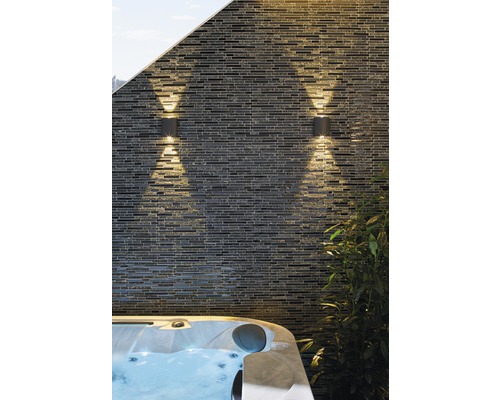 Deux luminaires d''extérieur sur un mur en pierre à côté d''un bain à remous