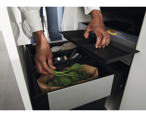 Système de tri des déchets avec plusieurs bacs et un couvercle, dans lequel une personne jette des déchets verts