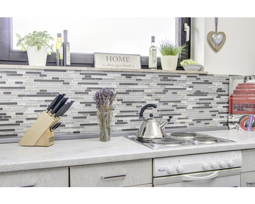 Küchenszene mit Mosaikfliesen, Kochfeld, Spüle und verschiedenen Küchenutensilien