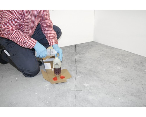 Un utilisateur verse un produit d''injection de fissures dans un flacon pour la réparation des fissures