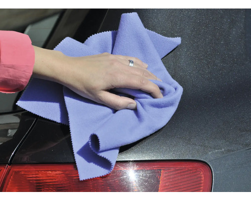 Person reinigt ein Auto mit einem Mikrofasertuch.