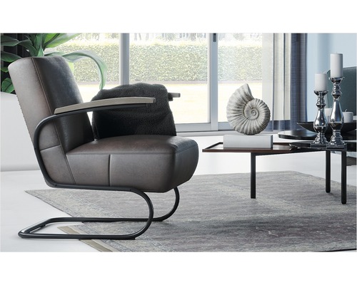 Wohnzimmer-Szene mit braunem Ledersessel, Kissen, Beistelltisch und Dekoration