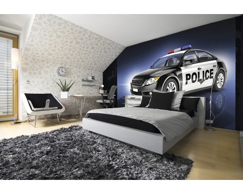 Chambre claire avec lit, bureau et papier peint photo d''une voiture de police