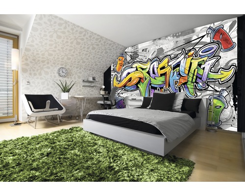 Chambre moderne avec papier peint graffiti, lit, bureau et tapis vert.