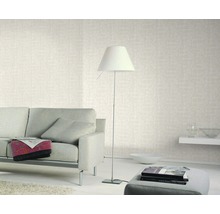 Salon avec canapé, lampadaire et papier peint à motifs pour une atmosphère lumineuse et conviviale.