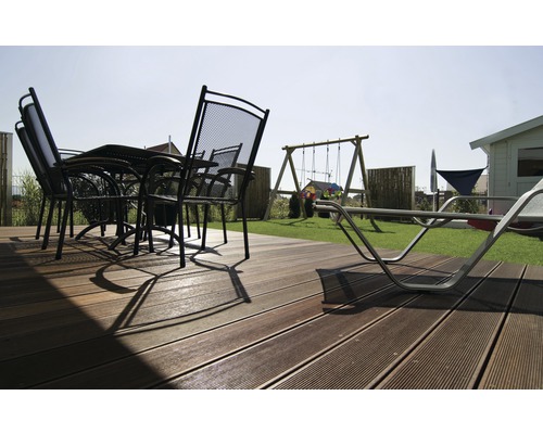 Terrasse mit Terrassendielen, Gartentisch, Stühlen und Spielplatz im Garten.