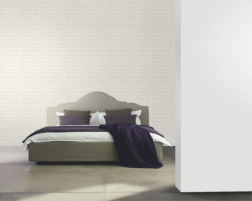 Chambre avec papier peint à motifs, lit et coussins décoratifs