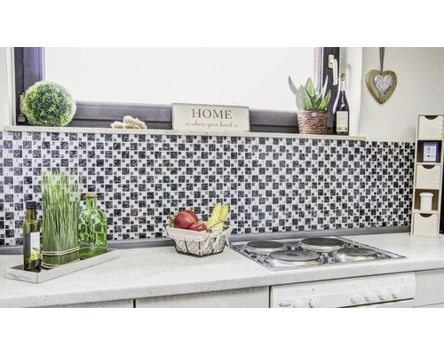 Scène de cuisine avec mur en carreaux de mosaïque, plaque de cuisson et éléments décoratifs pour une atmosphère claire et organisée.
