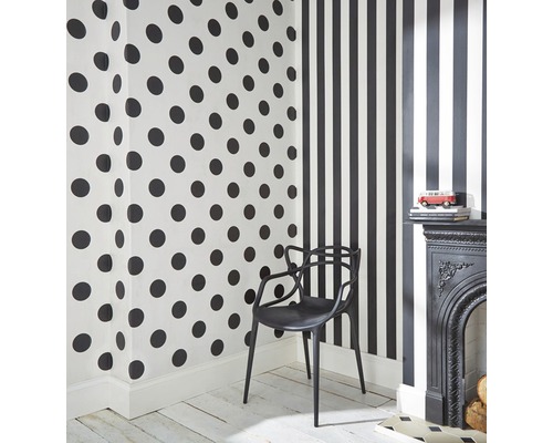 Zimmer mit gepunkteter Tapete, gestreifter Tapete, schwarzem Kamin und schwarzem Stuhl