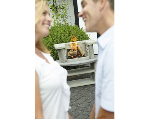 Beton Aussengrillkamin mit brennendem Holz und zwei Personen