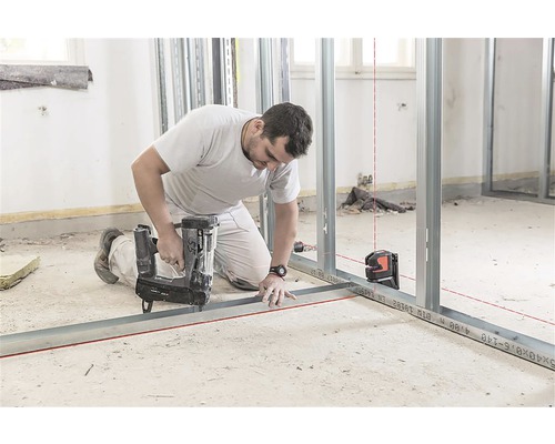 Handwerker befestigt Metallständerwerk mit einem Bolzensetzgerät, ausgerichtet mit einem Laser