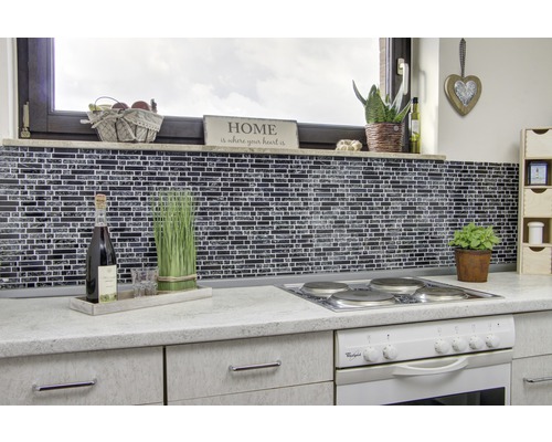 Scène de cuisine avec mur en mosaïque, cuisinière et décorations sur le plan de travail.