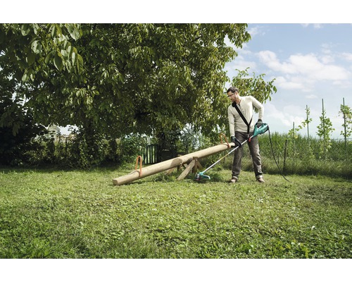 Mann arbeitet mit einem Rasentrimmer im Garten.