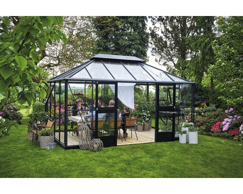 Gewächshaus mit Glaswänden und -dach im Garten, mit einer Gruppe von Personen darin.