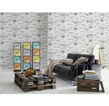Wohnzimmer mit grauer Couch, Regal mit farbigen Schubladen und Weltkarten-Tapete