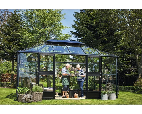 Gewächshaus mit Pflanzen und zwei Personen im Garten