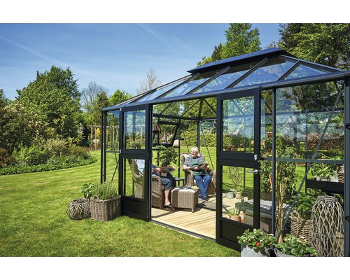 Gewächshaus mit Sitzbereich und Pflanzen im Garten