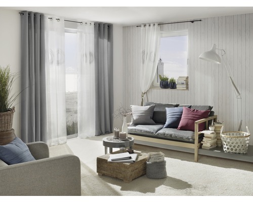 Salon avec canapé, fauteuil, rideaux et éléments décoratifs pour une ambiance chaleureuse.