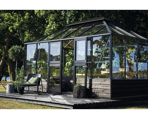 Gewächshaus mit Glaswänden und dunklem Rahmen auf Holzterrasse im Garten