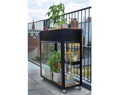 Rollbarer Pflanztisch mit Pflanzgefäßen und Gartenzubehör auf einem Balkon