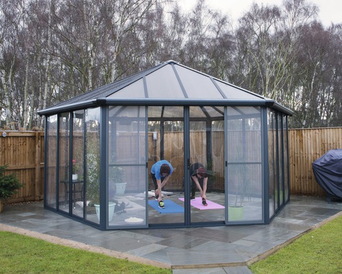 Freistehender Pavillon mit Glasschiebetüren und zwei Personen beim Dehnen auf Yogamatten