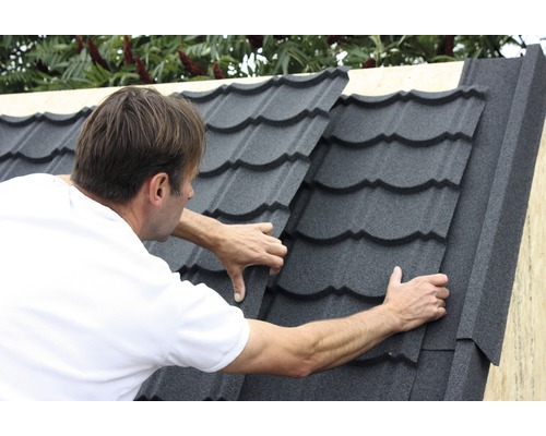 Un homme pose des tuiles sur un toit