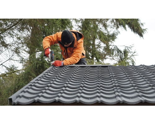 Artisan pose des plaques de toiture avec une visseuse sans fil