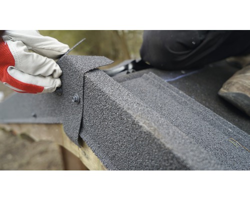 Gros plan sur l''installation de bardeaux de toiture avec des vis par une personne portant des gants.