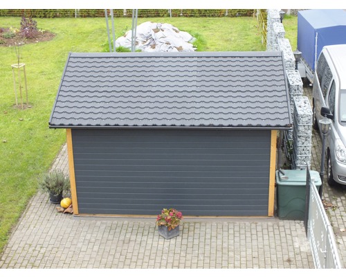 Garage avec porte roulante grise et toit en tuiles dans le jardin