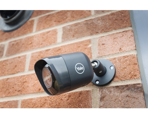 Caméra de surveillance Logo Yale montée sur un mur en briques