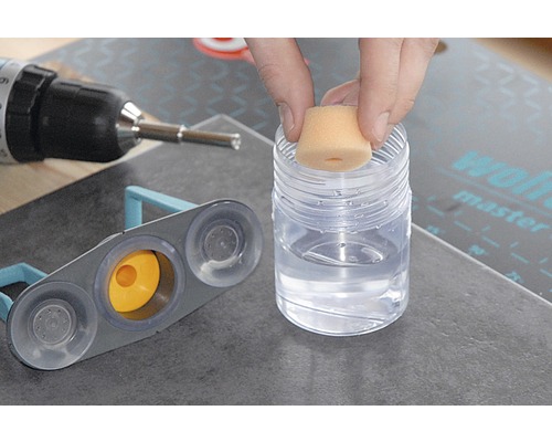 Outil de carreleur en utilisation avec éponge, récipient avec liquide de nettoyage et perceuse