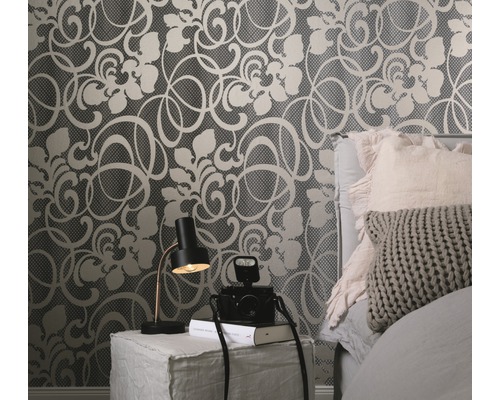 Dekoratives Schlafzimmer mit floral gemusterter Tapete, Nachttischlampe und Kamera