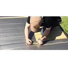Mann misst Folie mit einem Massband für Bauarbeiten.