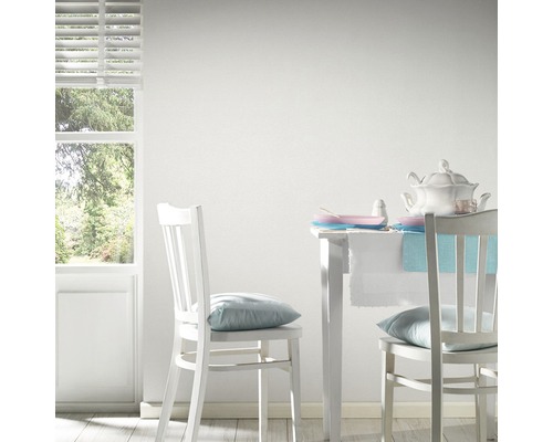 Pièce lumineuse avec des meubles blancs, une table et des chaises mises en scène.