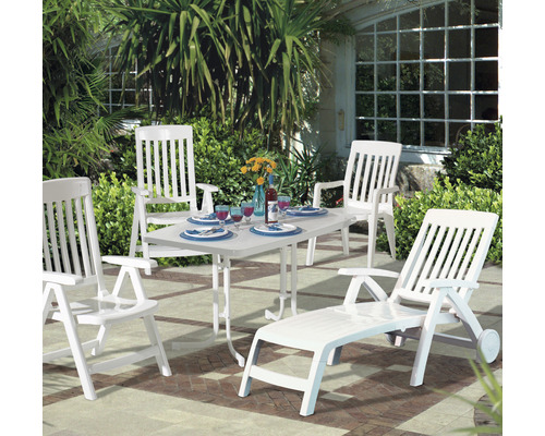 Gartenszene mit weißen Gartenmöbeln: Tisch, Stühle und Liege