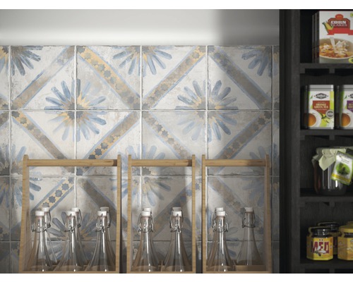 Wandfliesen mit floralem Muster und einem Regal mit Flaschen im Hintergrund.